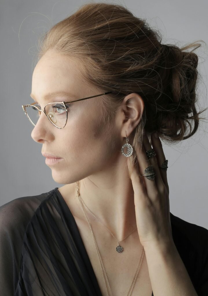 Stylish portrait of a woman wearing glasses and elegant jewelry, exuding sophistication.